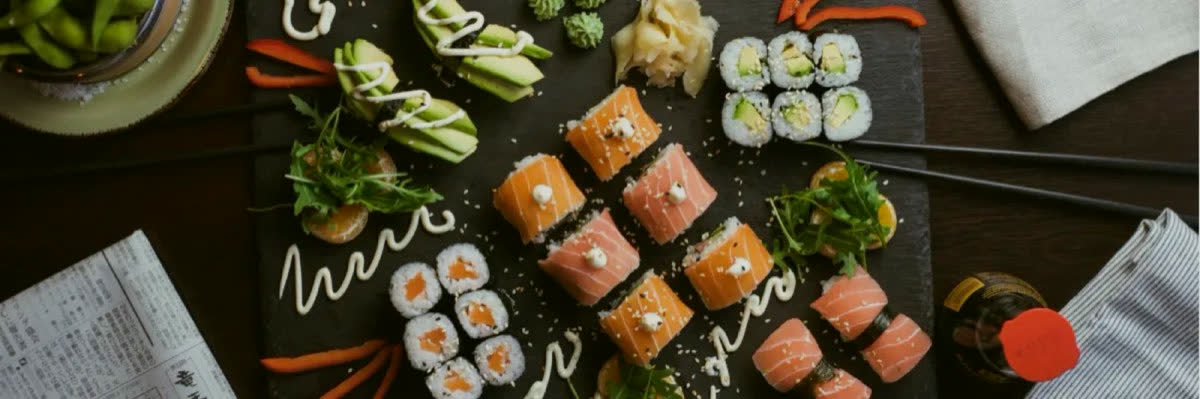 An overhead spread of Blue Fish rolls, nigiri and sides on dark slate