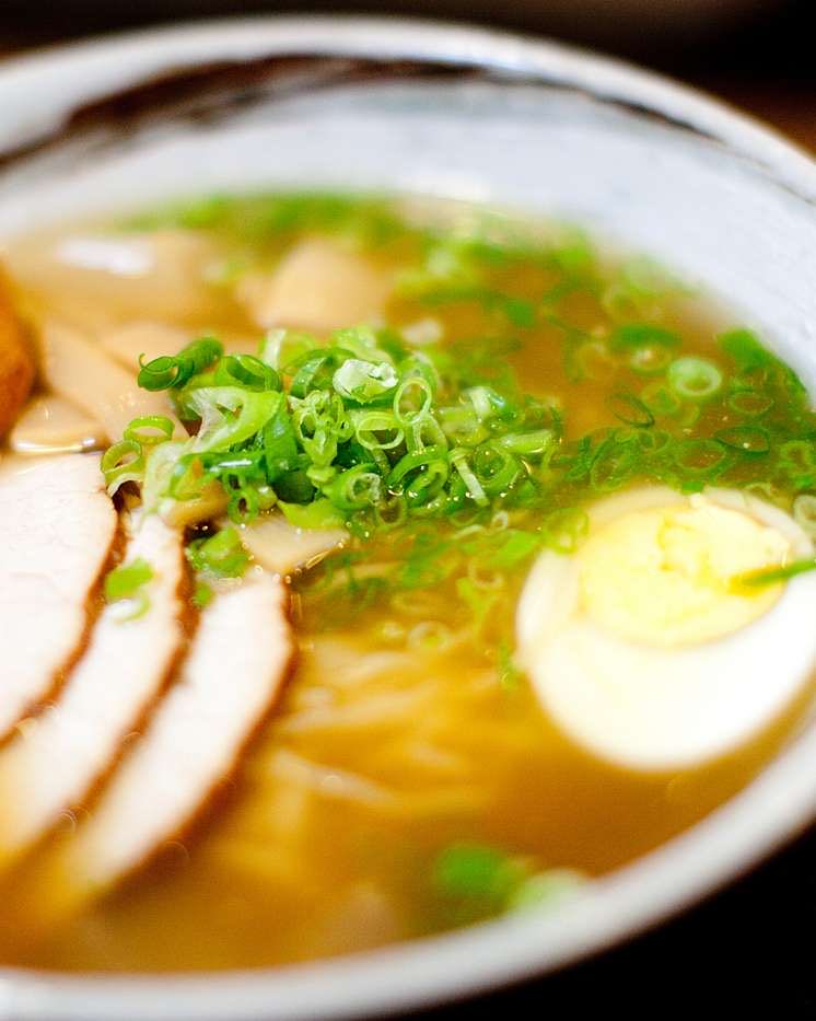 A bowl of ramen: sliced pork, scallions, a halved egg, and noodles in broth