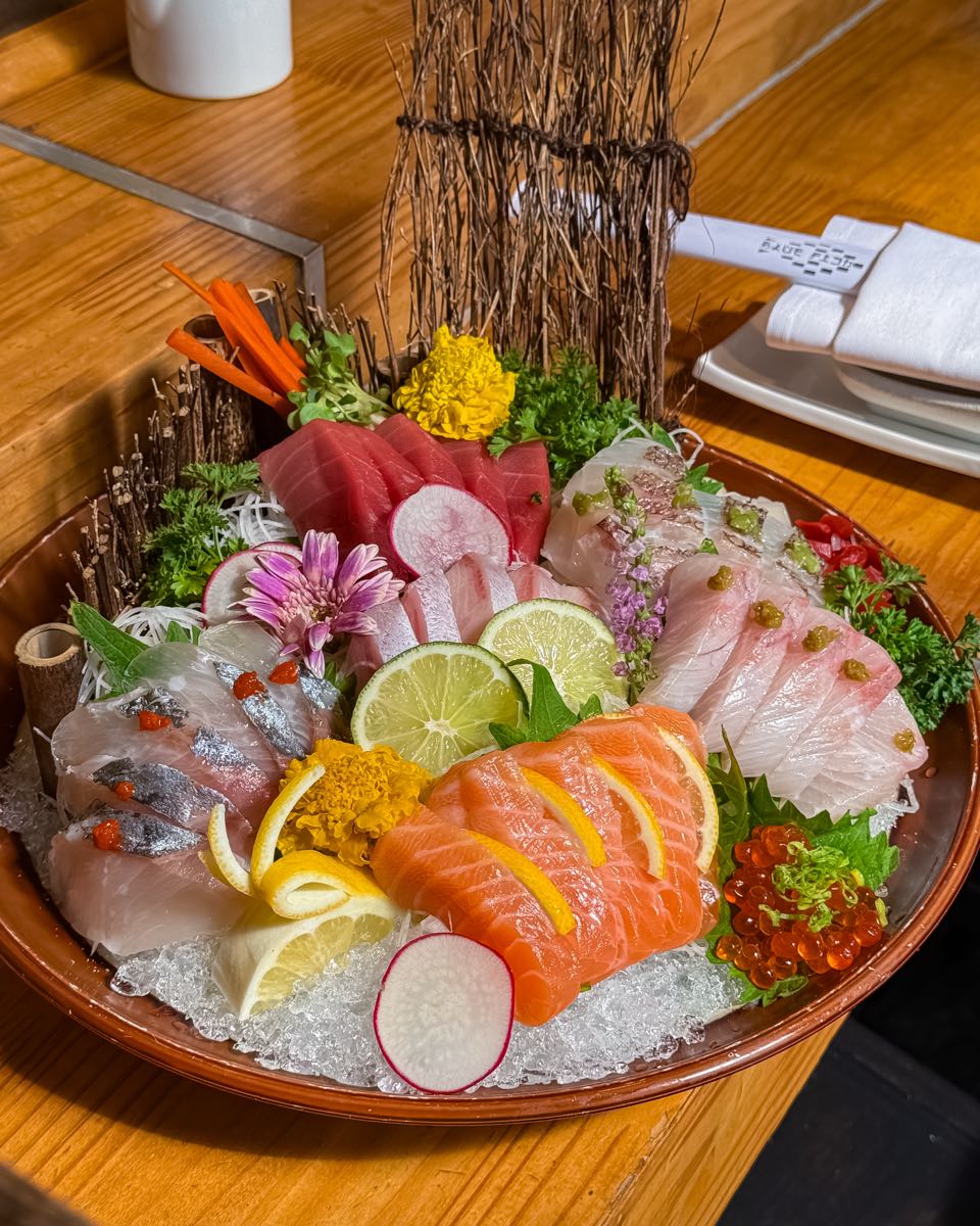 A sashimi platter over ice: salmon, tuna, yellowtail, and white fish with salmon roe, lemon, and radish