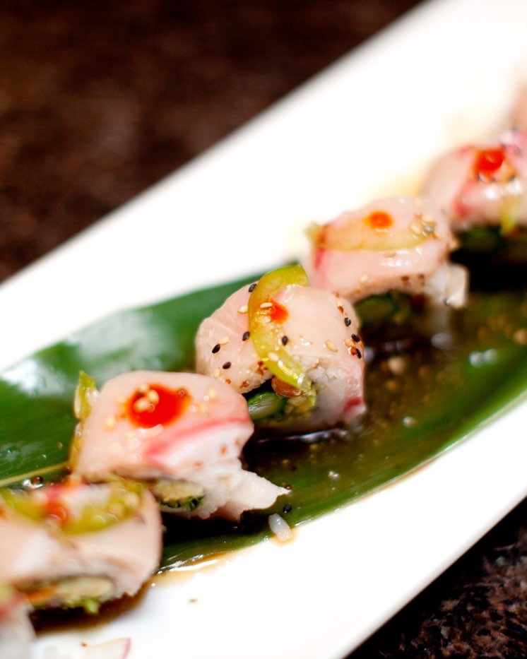 The Yellow Fever Roll on a long plate, yellowtail and sliced jalapeno over each piece